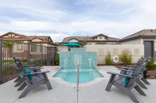 The pool area at our apartments for rent in Peoria, AZ, featuring a fountain surrounded by Adirondack chairs.