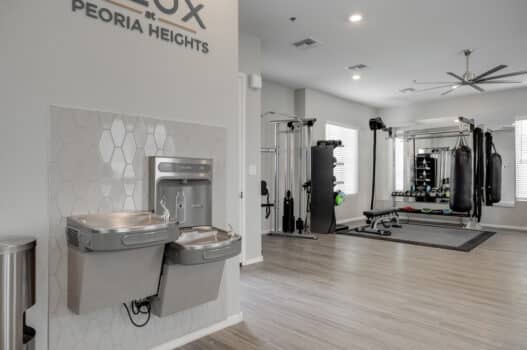 The fitness center at our rental homes in Peoria, featuring wood grain flooring, a water fountain, and exercise equipment.